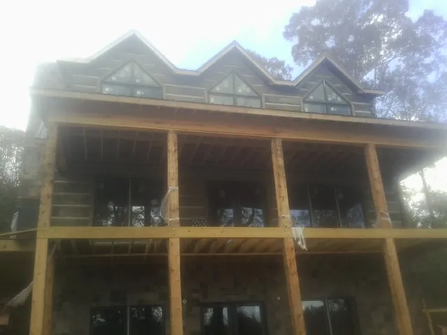 Dormers and porch framing on a large log home under construction — Roof Coating work by our crew in Garnett