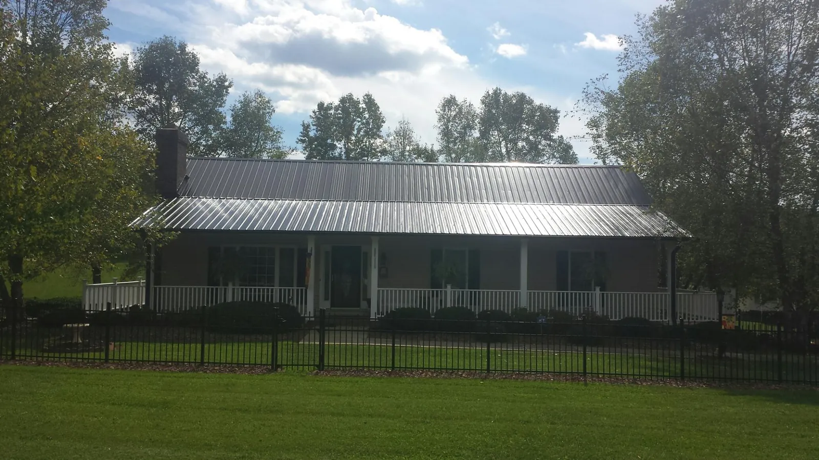 Gray metal roof on a brick ranch with a full width front porch — Gutter Guard Installation work by our crew in Garnett