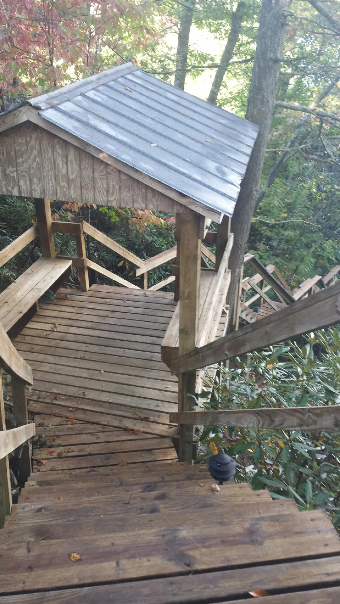 Metal roofed shelter over wooden steps on a wooded walkway — Skylight Repair & Installation work by our crew in Garnett