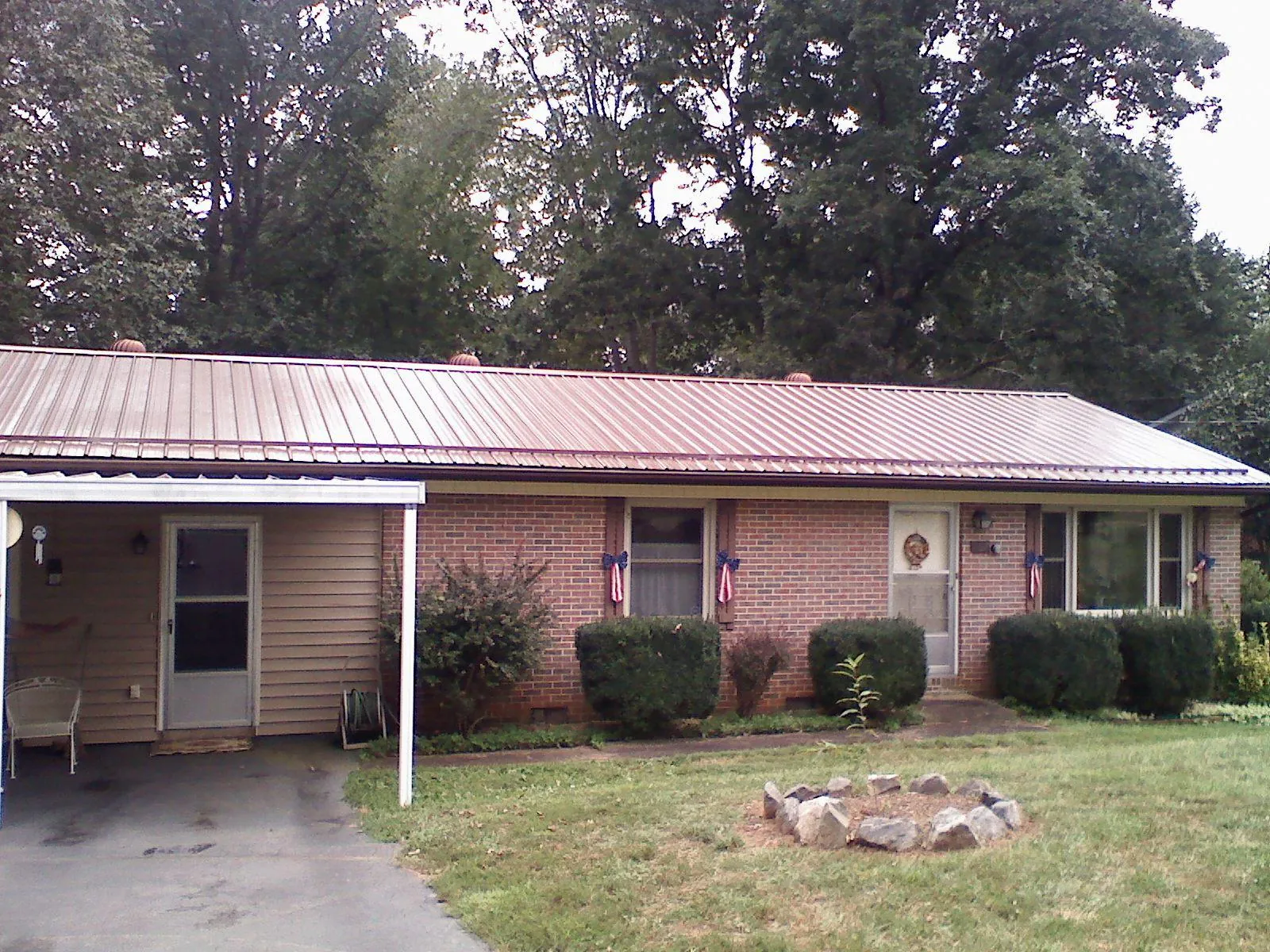 Bronze metal roof and carport on a brick ranch home — Roof Repair work by our crew in Garnett