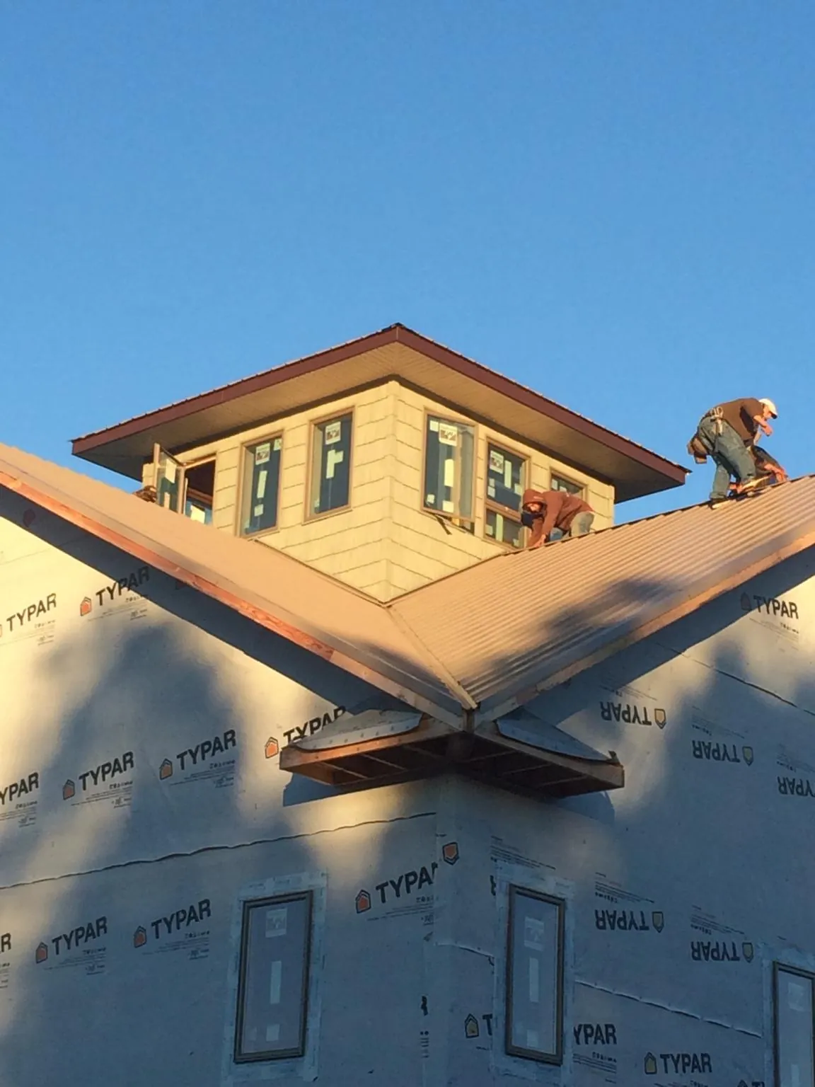 Roofers working around a rooftop cupola on a new metal roof at sunset — Roof Waterproofing in Garnett by Roofing Brothers